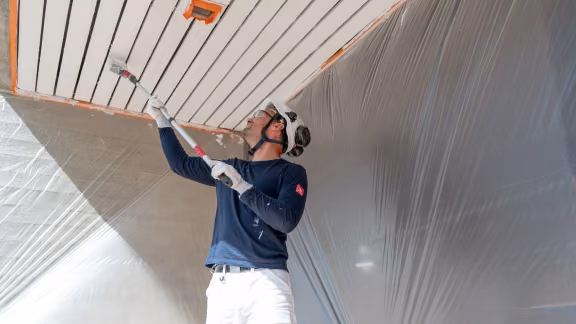 A painter painting an exterior wooden area