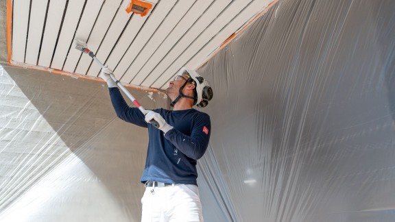 A painter painting an exterior wooden area