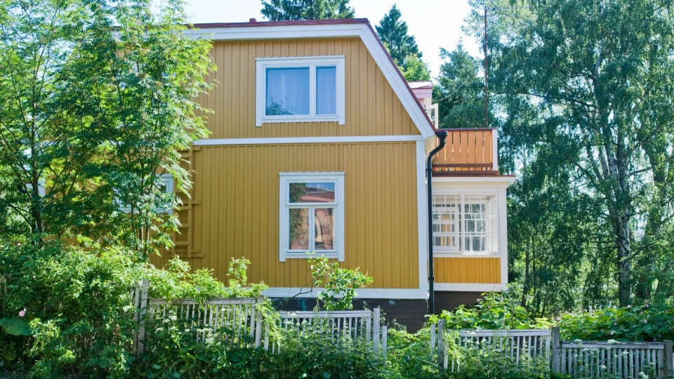 traditional yellow wooden house surrounded by trees
