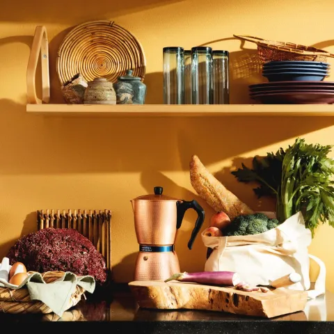 bright warm yellow wall behind busy kitchen desk and shelf