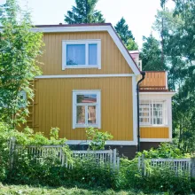 traditional yellow wooden house surrounded by trees