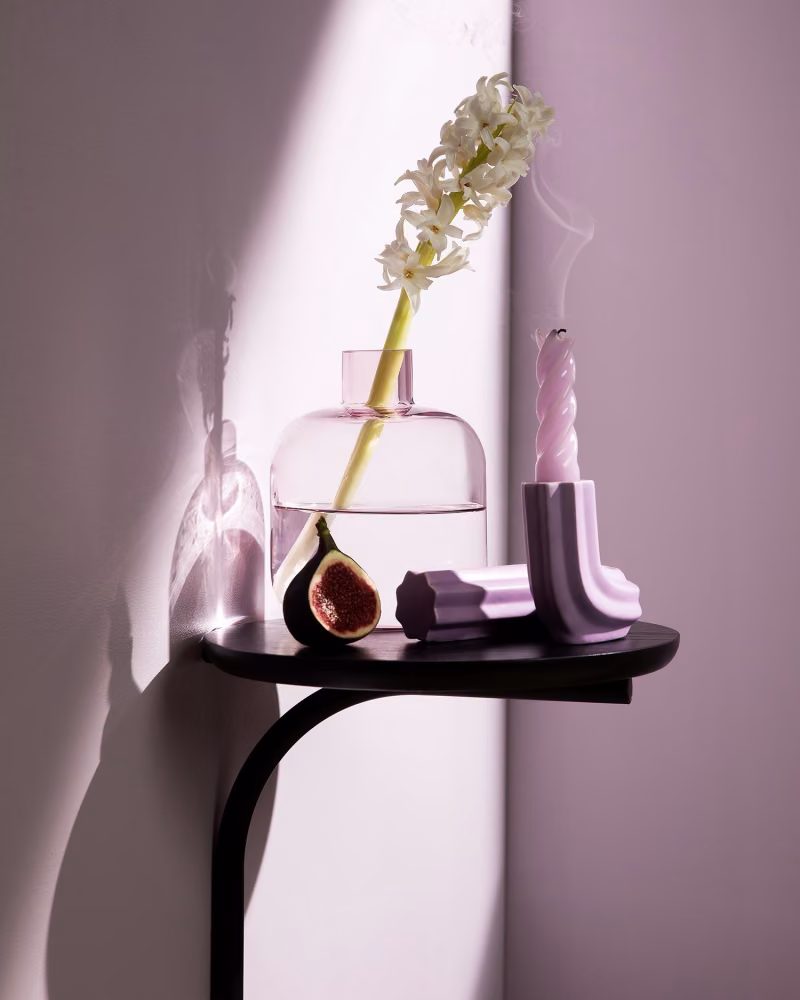 dark wooden shelf with decor items in front of soft lilac colour wall