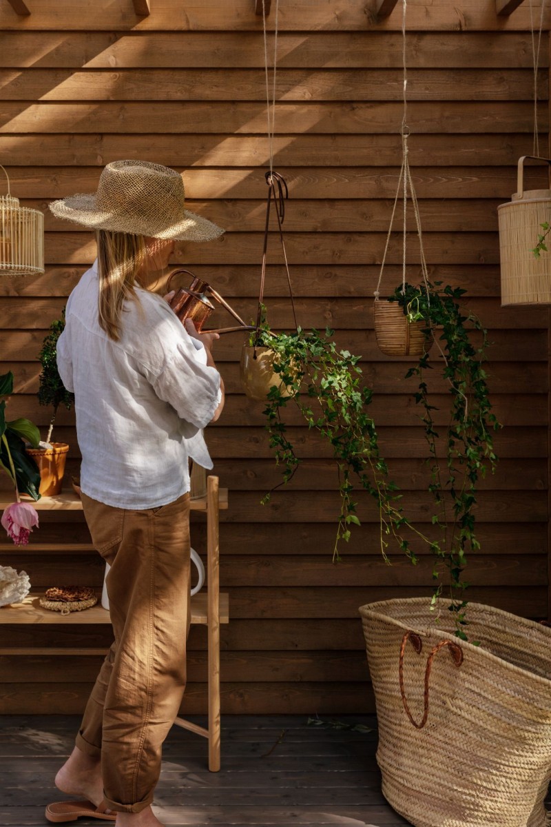 woman watering plants in wooden pergola